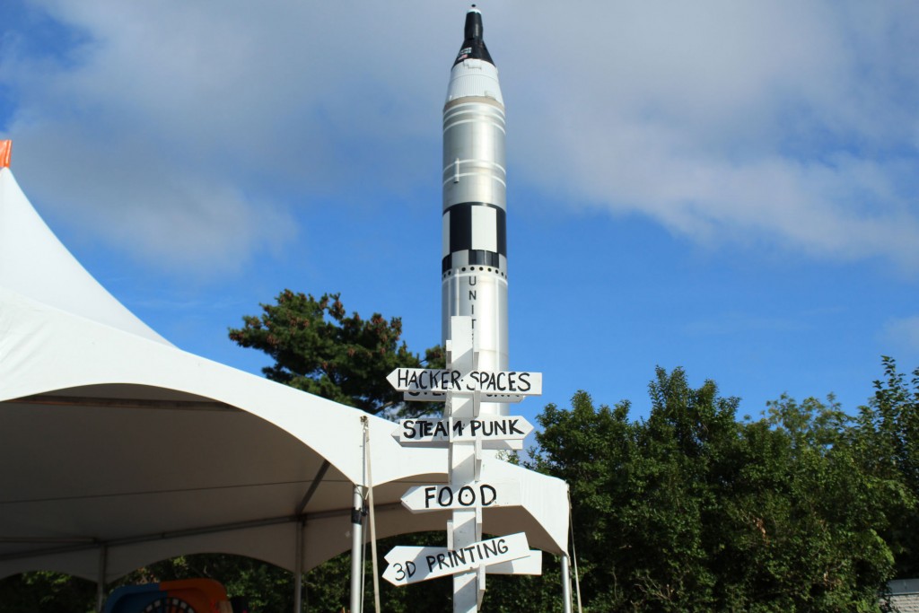 A signpost with one of the 1964 World's Fair rockets in the background.